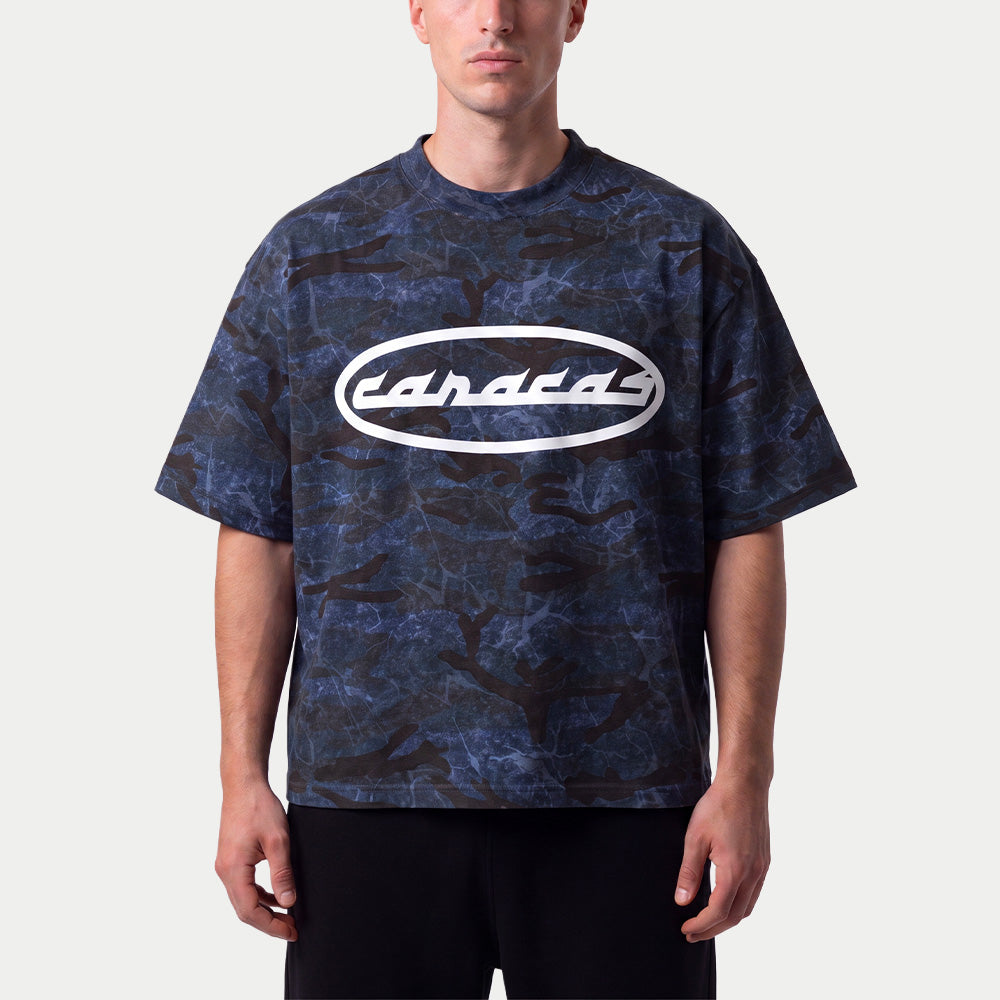 Hombre llevando la camiseta boxy de camuflaje azul «Caracas» de Caracas Merch con el óvalo blanco